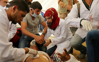 Volunteer paramedic Razan Al-Najjar, 21, killed by the Israeli occupying forces on 1 June 2018, east of Khuza’a, treats injured Palestinians during the Great Return March